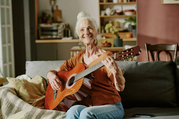 istock Elderly Woman Smiling While Playing Acoustic Guitar Indoors 2186277889