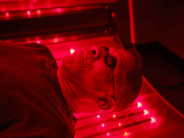 A mature man on an LED light bed, receiving red light therapy.