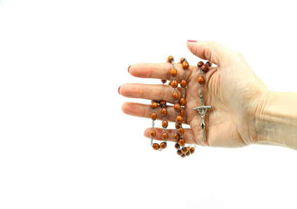 Woman´s hand holding a rosary with brown beads.