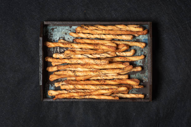 Popcorn-studded breadsticks in rustic wooden tray.