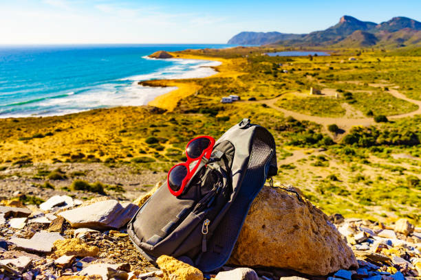 Sunglasses and backpack, summer walking equipment on mediterranean sea coast. Murcia region, Calblanque Regional Park in Spain. Hiking, camping, active lifestyle.
