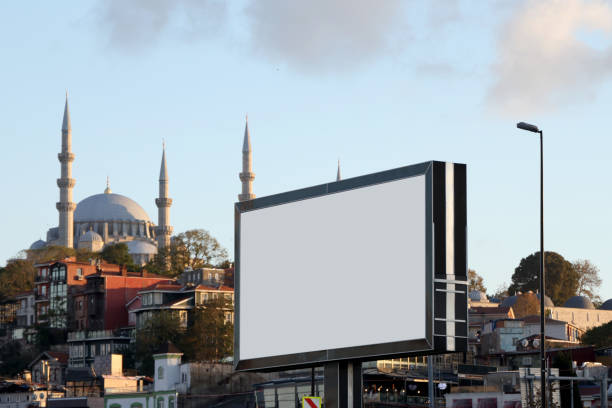 photo shows an empty white sign with a wooden frame against a mountainous landscape. The mountains are in perspective, with clouds. focus is on the sign. Perfect for text placement.