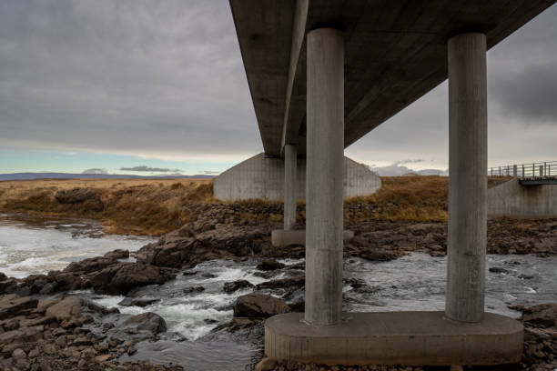 Simple Laxa bridge across a river, surrounded by yellow - golden high autumn grass. Cloudy sky. Close to city Budardalur, West Iceland.