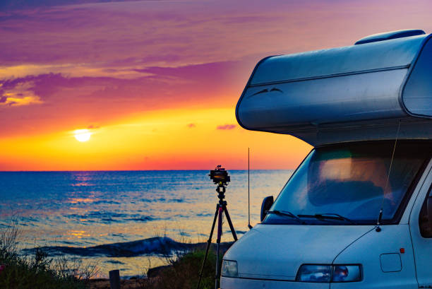 istock Camper and camera on tripod on beach at sunrise 2186315163