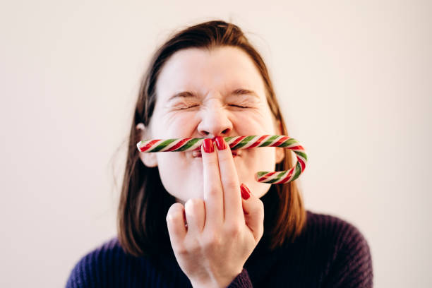 istock Young fun woman posing with candy cane in light background. 2186334826