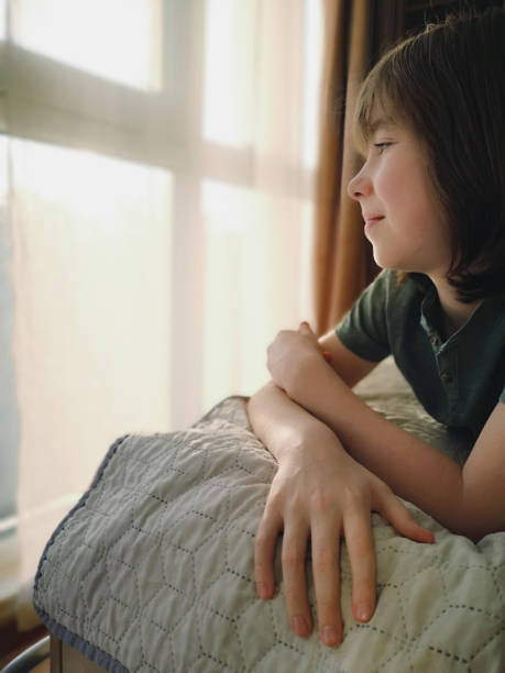 istock Child relaxing at home while looking out the window on a sunny day 2186335791