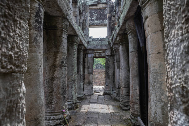 Ancient stone statue carved in a temple niche at Angkor Wat, Cambodia. Weathered relief and intricate carvings surround the serene figure, reflecting Southeast Asian temple artistry and history.