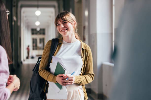 istock Young Student Smiling in University Hallway Holding Books 2186344312