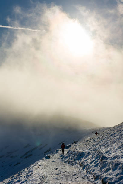 istock Hikers on a small ice and snow covered trail with low cloud behind 2186344519
