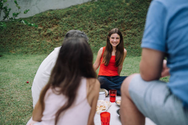 Two families having picnic at a table in a park, vertical