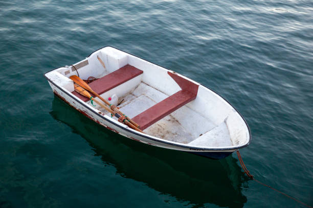 A solitary white rowboat gently floats on the calm blue water, secured by a rope. The serene scene evokes feelings of tranquility and peacefulness, ideal for themes of relaxation.