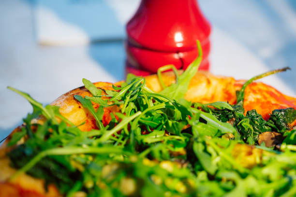 A vibrant close-up image of a delicious vegetable pizza topped with fresh arugula and spinach, highlighting a colorful and appetizing scene perfect for healthy eating concepts.