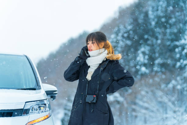 istock Asian woman using mobile phone calling for assistance while her vehicle breakdown in snow. 2186368312