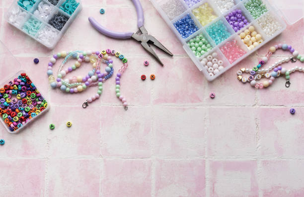 istock Colorful beads and jewelry making tools arranged on pink tile surface 2186370211