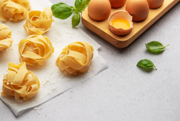 istock Fresh tagliatelle pasta nests with eggs and basil leaves on baking paper 2186370227