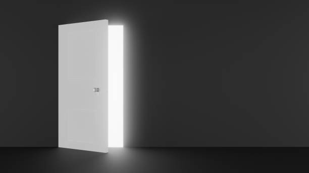 istock A white door opens into a dark room, revealing a bright light 2186370769