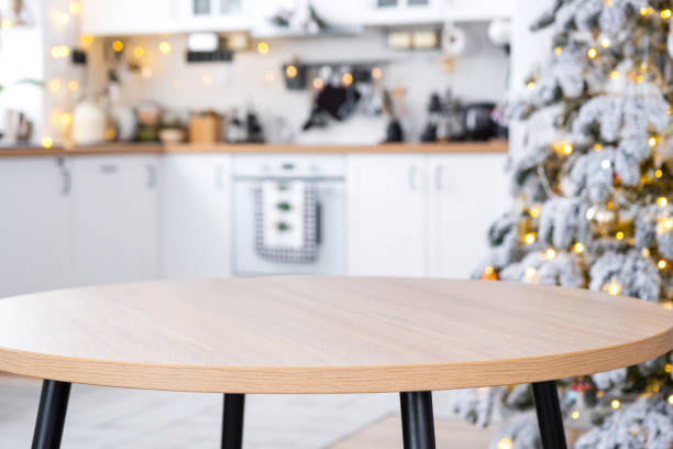 istock Round empty table to demonstrate the product with space for text in white kitchen, modern interior with a Christmas tree and fairy lights. New Year, Christmas mood, cozy home. 2186376323