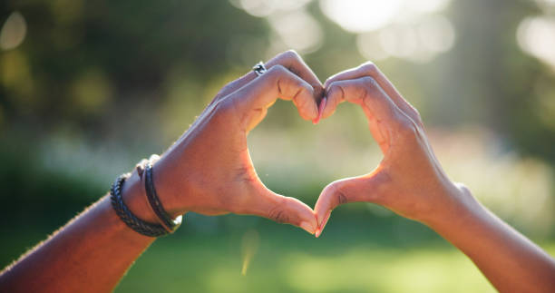 istock Love, heart and hands of couple in nature with gesture for support, trust and commitment on date outdoors. Emoji, symbol and people with shape together for bonding, relationship and care in park 2186376546
