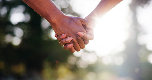 istock Couple, forest or holding hands with sunshine for support, hope or bonding together in nature. Closeup, man or woman with touch, connection or love for commitment, holiday or outdoor weekend in woods 2186376549