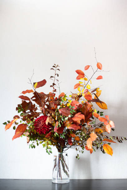 istock Multicoloured autumn bouquet on a table. Bunch of colorful fall branches and red chrysanthemum flower in glass vase at home interior. 2186382939