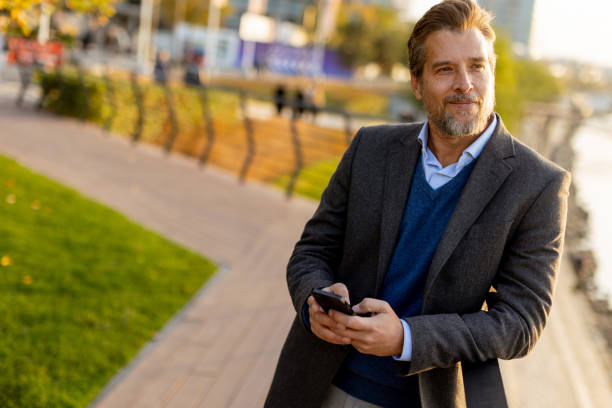 istock A business professional enjoys a sunny afternoon stroll by the river while checking his phone in a modern urban park 2186389803