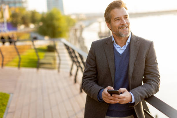 istock A business professional enjoys a sunny afternoon stroll by the river while checking his phone in a modern urban park 2186389817