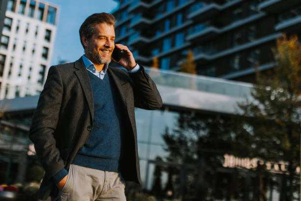 istock Businessman in smart attire walking while talking on phone in modern urban setting during sunny afternoon 2186389818
