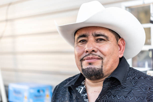 Smiling mature hispanic man looking at the camera wearing a cowboy hat