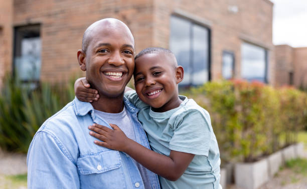 istock Happy father smiling while carrying his son outside their house 2186412049