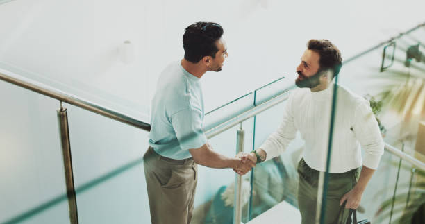 istock People, handshake and collaboration in office for business, agreement and communication with greeting. Partnership, stairs and men shaking hands in digital agency for meeting, welcome and teamwork 2186412848