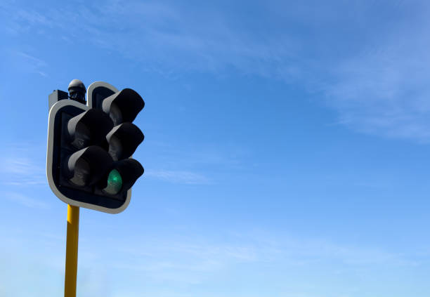 Green traffic light for cars on pole, blue sky background, Go signal concept