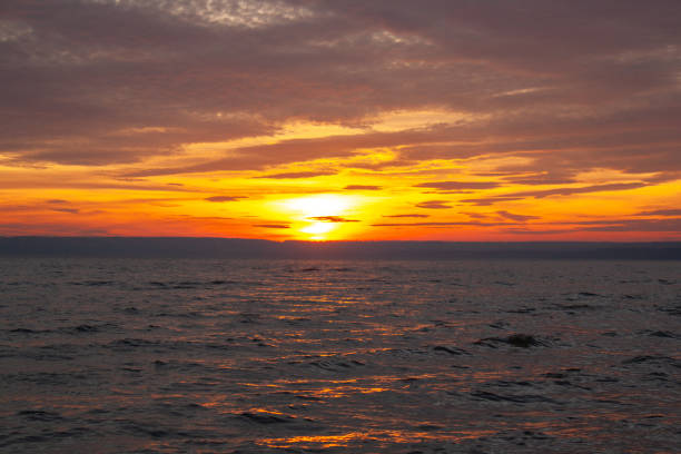 a colorful sky with the sun setting behind clouds