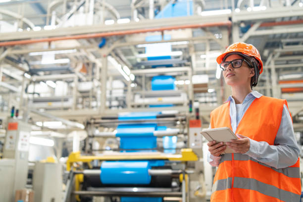 istock Engineer overseeing operations on tablet in bright industrial plant wearing safety gear. 2186414122
