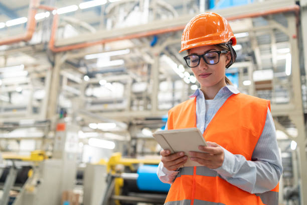 istock Female engineer using a tablet in a busy factory environment with machinery in background. 2186414135