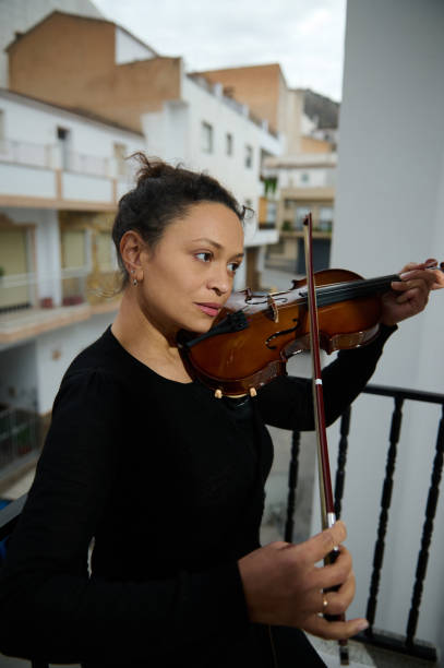 istock Woman practicing violin on urban balcony during overcast day 2186417672