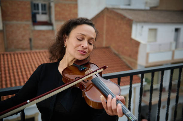 istock Woman playfully playing violin on balcony with closed eyes 2186417705
