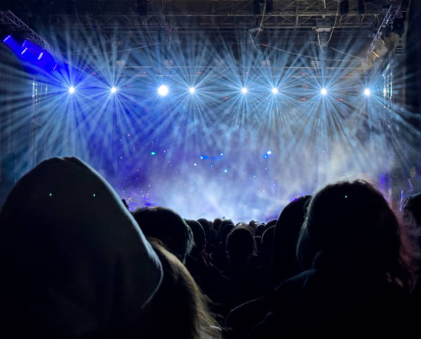 istock A crowd of people are watching a concert with lights shining on them 2186418804