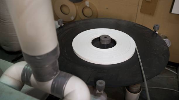 istock Industrial machine actively unwinding white tape in a factory environment. 2186420708