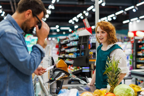 istock Customer making a purchase and paying at supermarket checkout while talking on phone 2186420786