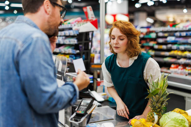 istock Customer paying with contactless card while talking on phone at supermarket checkout 2186420788