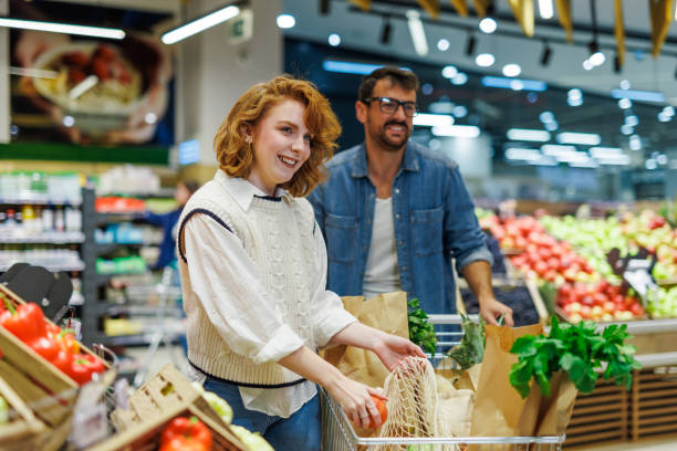 istock Couple choosing fresh produce at grocery store using reusable bag 2186420791
