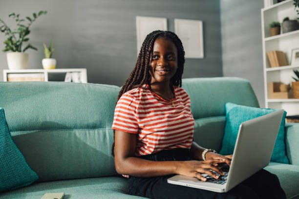 istock Young black woman working from home on laptop smiling at camera 2186421971