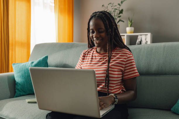 istock Young woman working remotely from home office using laptop on sofa 2186421979