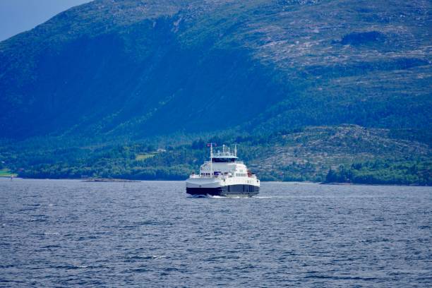 Kristiansund, Norway – July 14, 2024: A ferry cruising on a serene lake with a backdrop of lush green mountains on a clear day.
