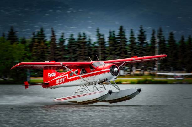 Anchorage, United States – July 24, 2024: A red seaplane taking off from a lake with a forested background