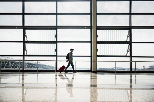 istock Man walking with suitcase at airport terminal. 2186429563