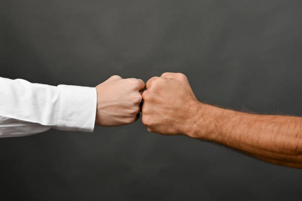 istock Two men bumping fists isolated on grey background. concept 2186432665