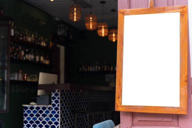 A large blank billboard in front of a cafe on a cobbled street. Blank banner on window office template. Promotional banner on the store window mock up. Clipping path.