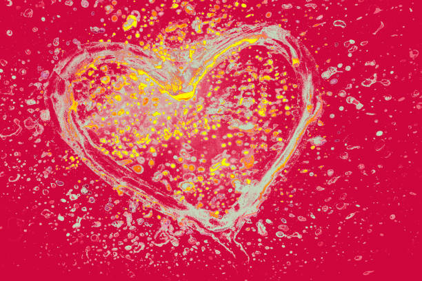Heart on a glass with paint splash effect on it on a black background