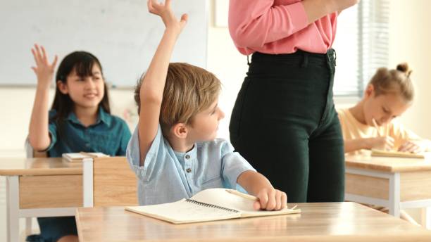 istock Boy raise hand for volunteering to answer while teacher walking pass. Pedagogy. 2186443903